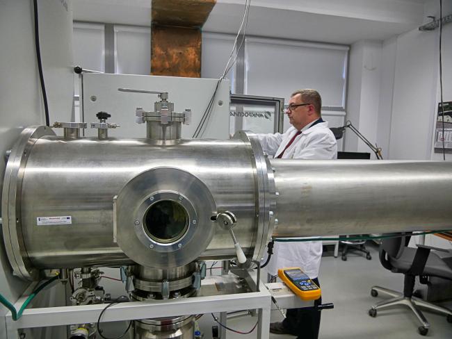 Dr Marek Barlak przy komorze próżniowej implantatora jonów w Narodowym Centrum Badań Jądrowych w Świerku. (Źródło: NCBJ)
